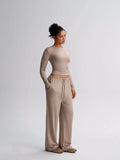 Woman wearing a beige long-sleeve top and wide-leg pants on a white background