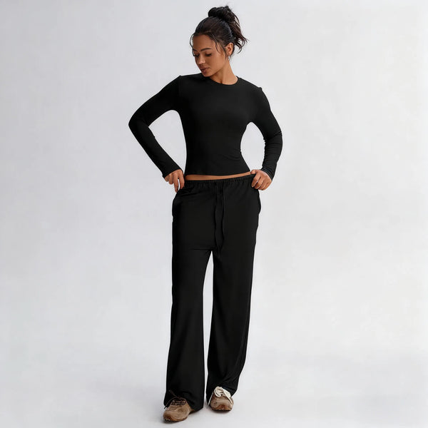 Person wearing a black long-sleeve top and black pants on a white background